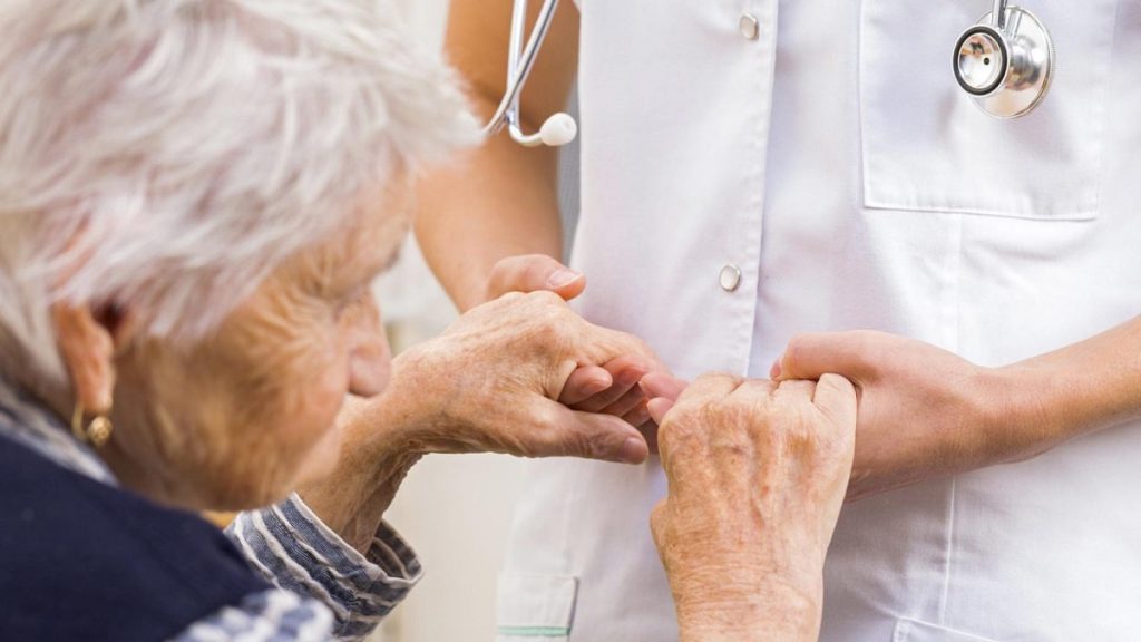پرستاری که دستان بیمار سالخورده را گرفته